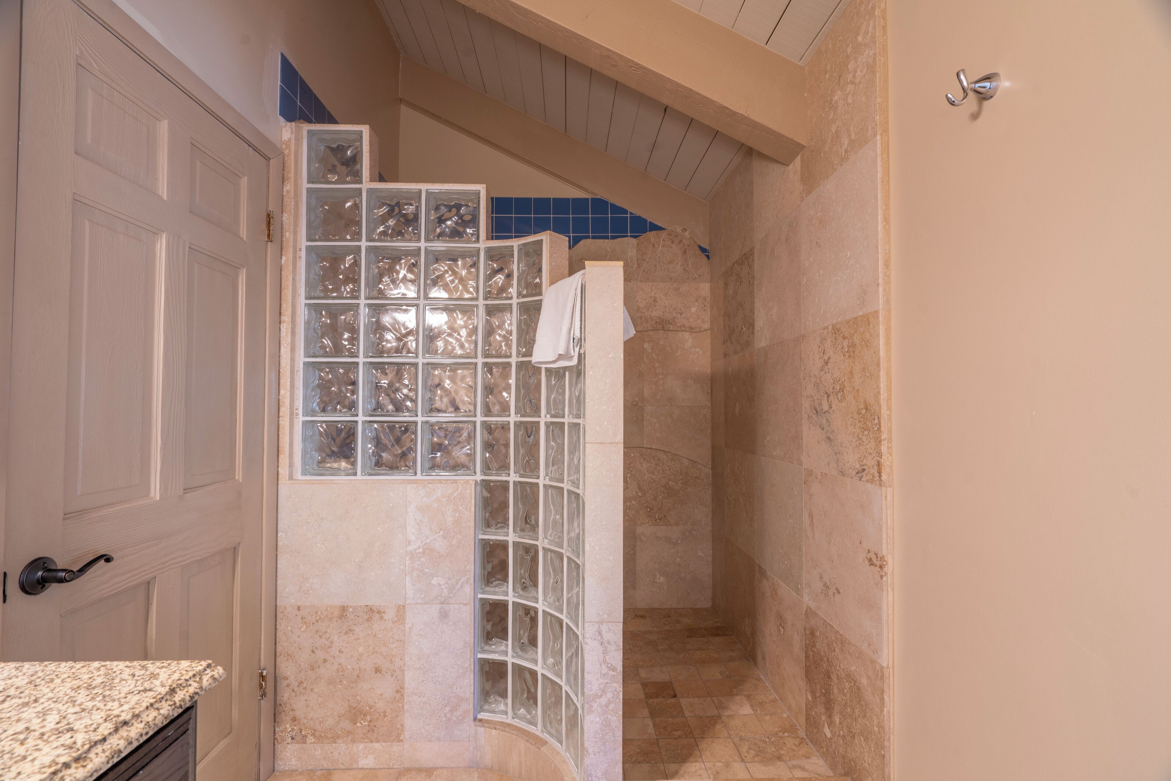 A bathroom with a glass shower enclosure, a white door, and a tiled floor.