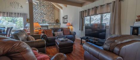 A spacious living room with leather sofas, a flat-screen TV, and a stone fireplace.