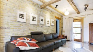 A cozy living room with a leather sofa, a cowhide rug, and framed pictures on a brick wall. - Trädgårdshuset i Sankt Olof (Sankt Olof)