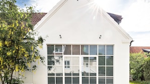 A modern building with a large garage door and a clear sky. - Trädgårdshuset i Sankt Olof (Sankt Olof)