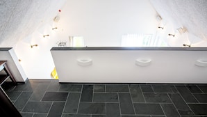 A modern hotel lobby with a high ceiling, dark tiled flooring, and a central reception desk with a glass partition. - Trädgårdshuset i Sankt Olof (Sankt Olof)