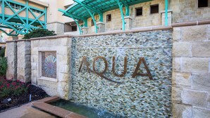 Facciata di un edificio con la scritta in evidenza 'AQUA', che suggerisce un locale a tema acqua.