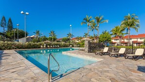 Ein Pool mit Liegestühlen und Palmen.