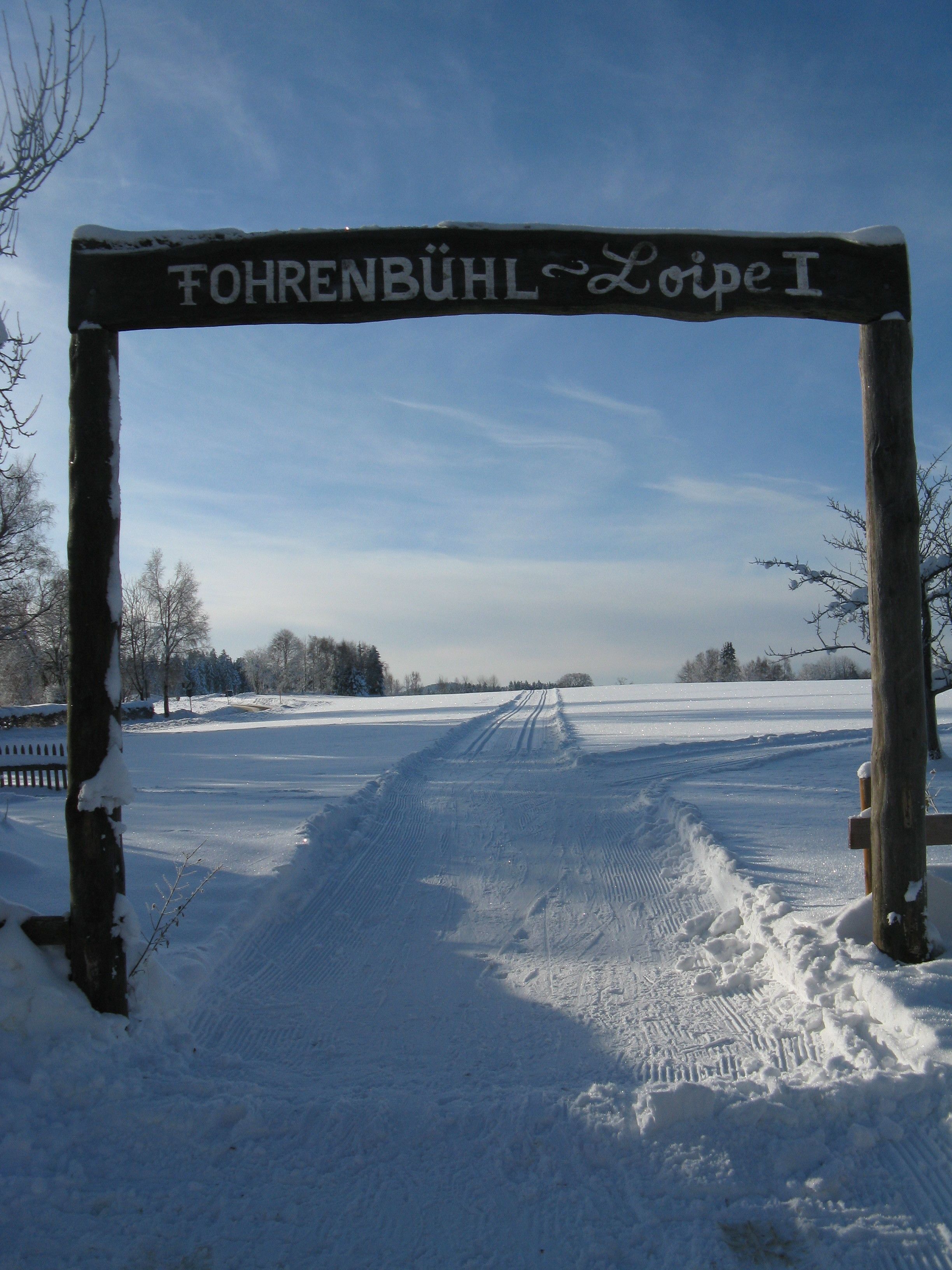 Un sendero cubierto de nieve que lleva a un cartel con la inscripción "FOHRENBÜHL Loipe I".