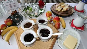 Una mesa con diversos alimentos, como manzanas, plátanos, queso y frascos de mermelada.