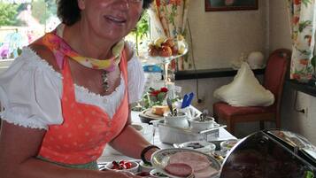 Een buffetopstelling met diverse gerechten en een persoon die bedient.