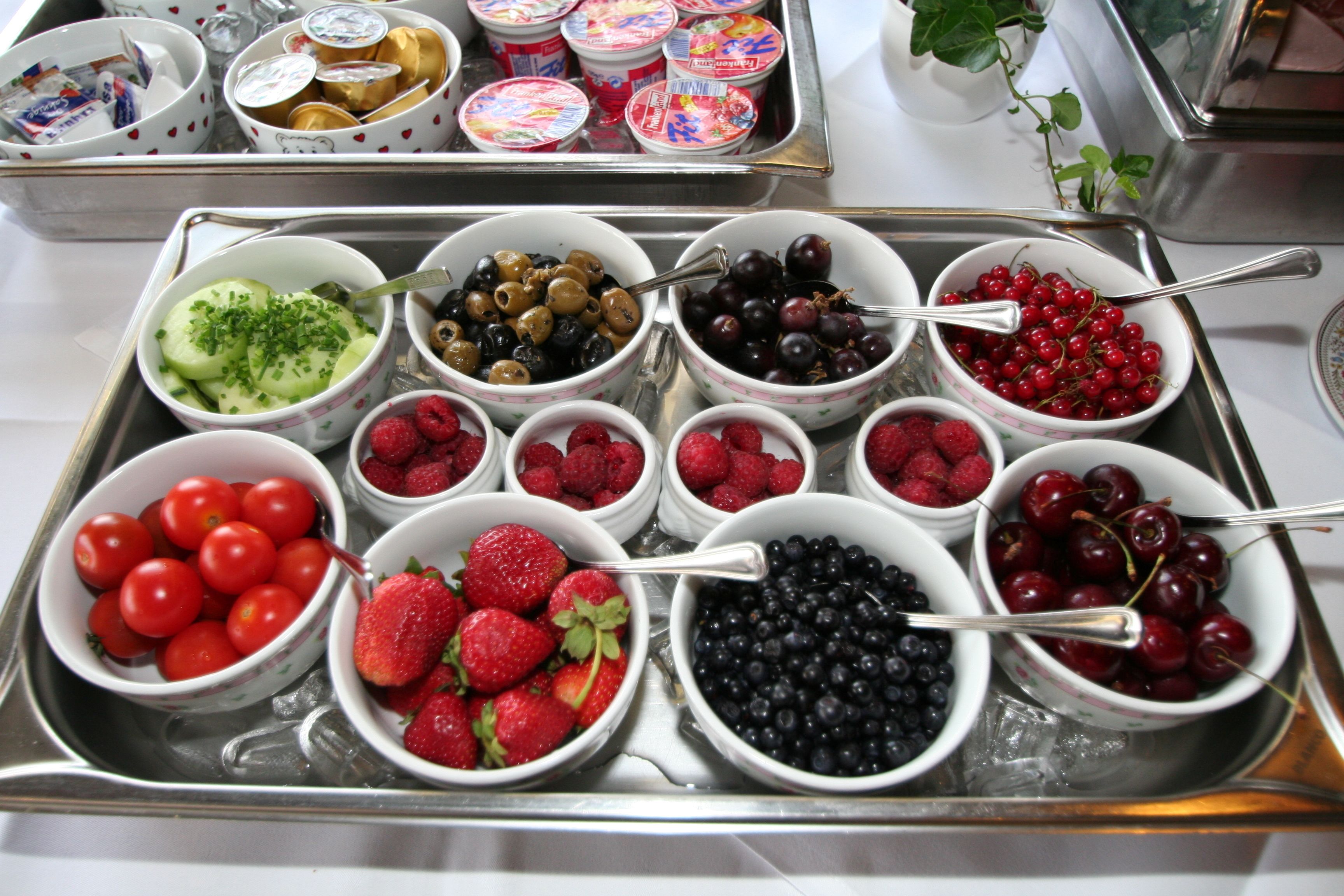 Un plateau contenant divers bols de fruits frais et des pots de yaourt.