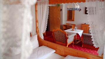 A cozy room with a wooden bed, a small table with a white tablecloth, and a chair.