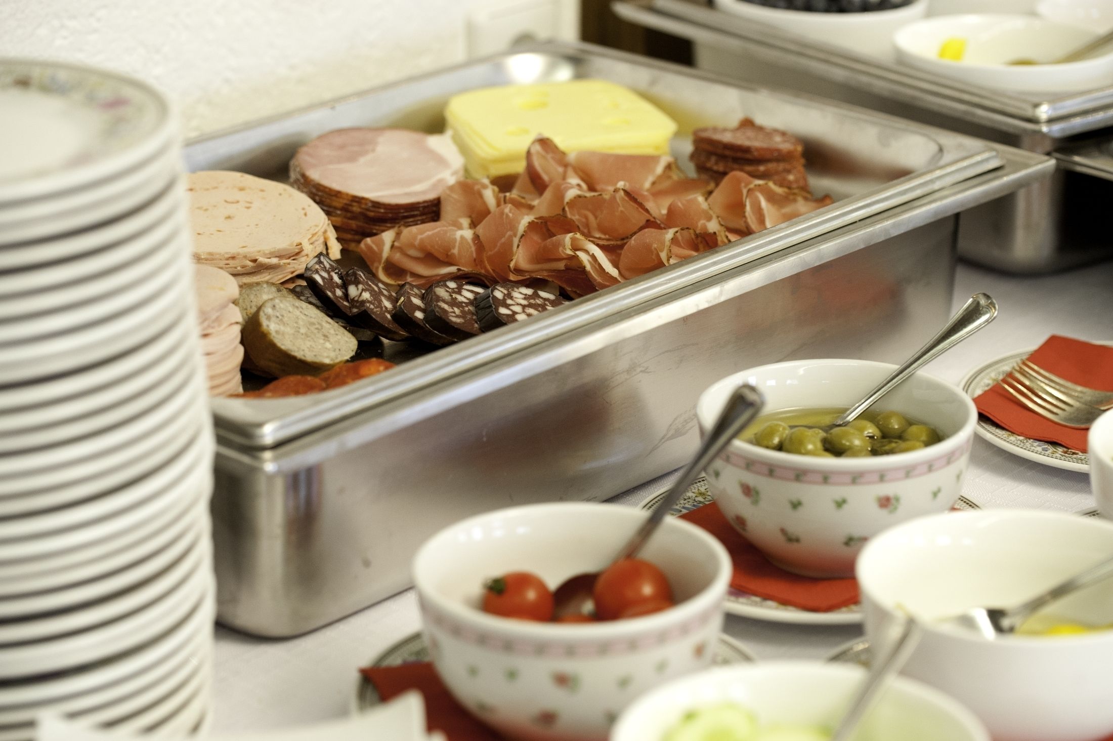 A buffet with various food items including meats, cheeses, and olives.