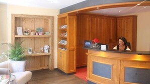 A reception area with wooden cabinets, a reception desk, and a seating area with a chair and a table.