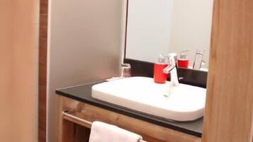 A modern bathroom with a glass sink, wooden vanity, and a large mirror.