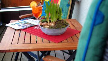 Een houten tafel met een kleurrijke stoel, een glas drinken en een schaal met bloemen.