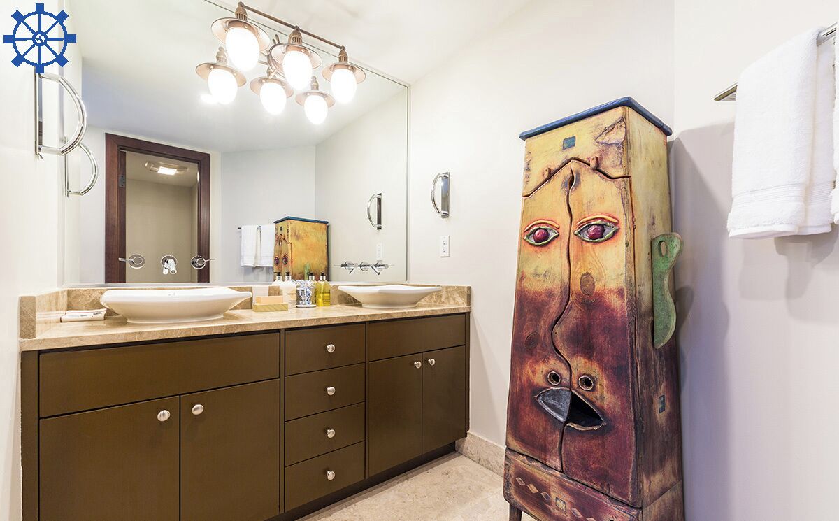 A bathroom with a double sink vanity, a large mirror, and a unique cabinet with a face painted on it.