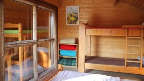 A wooden cabin room with bunk beds, a window, and a painting on the wall. - Chalets Etape du Camping Le Bivouac (Pont-du-Navoy)