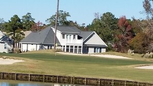 A golf course with a pond, a clubhouse, and surrounding trees. - Updated condo with a fantastic view!



 (Calabash)