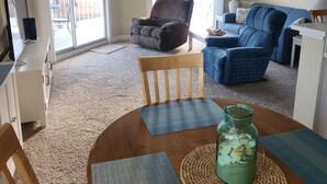 A living room with a wooden dining table, blue and gray sofas, a wooden chair, and a ceiling fan. - Updated condo with a fantastic view!



 (Calabash)