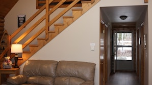 A wooden staircase leading to a loft, a leather sofa, and a lamp on a side table. - Quiet, Private and Comfortable  nestled on 8 acres of private property    (Lead)