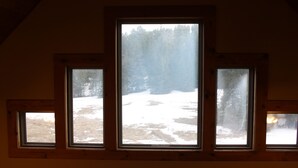 A room with three windows overlooking a snowy landscape. - Quiet, Private and Comfortable  nestled on 8 acres of private property    (Lead)