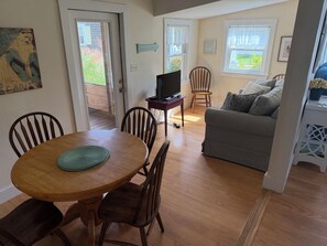 A living room with a grey sofa, wooden dining table, and chairs.