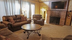 A cozy living room with leather sofas, a round coffee table, and a fireplace.