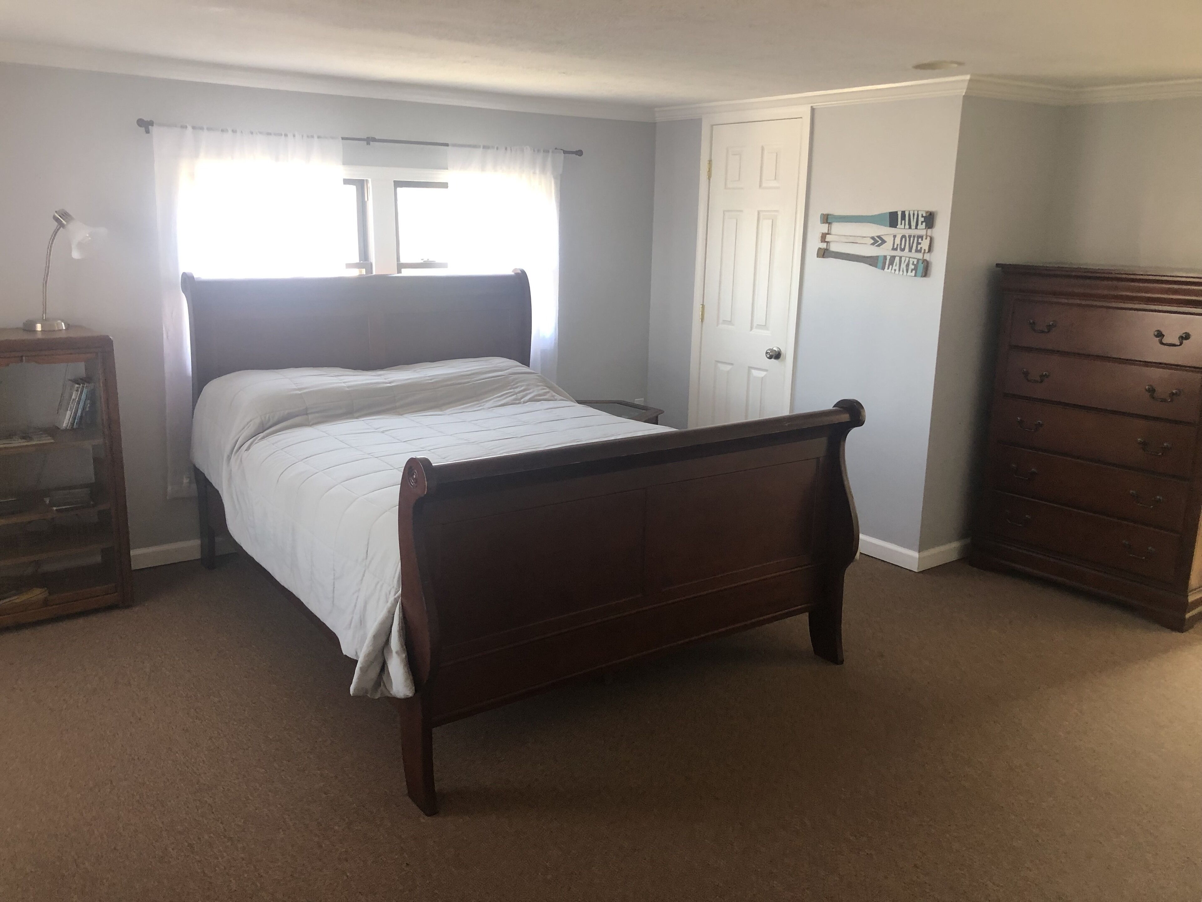 A bedroom with a wooden bed, a dresser, and a bookshelf.