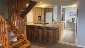 A kitchen with a wooden staircase, granite countertops, and a refrigerator. - OVERSIZED PORCH, LAKE FRONT, Mammoth Cave, Fast WiFi, Firepit, hiking (Mammoth Cave)
