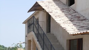 Ein zweistöckiges Gebäude mit Ziegeldach, einer Treppe mit schwarzer Geländer und einer kleinen Veranda.
