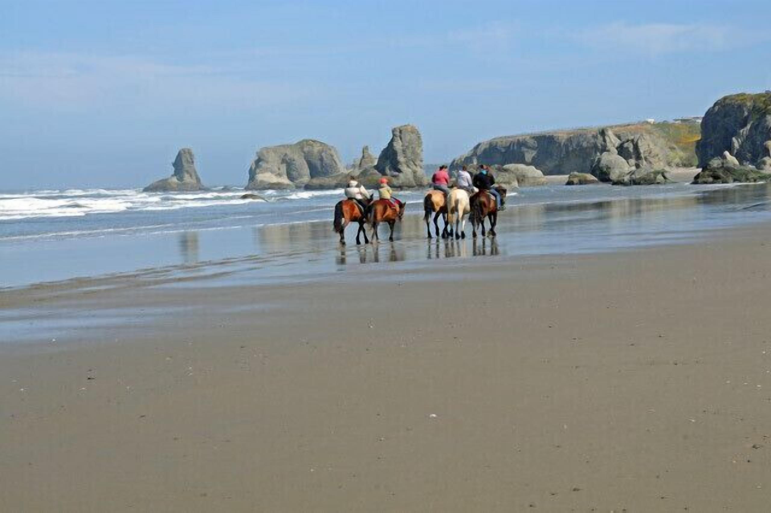 A beach with horses and riders.