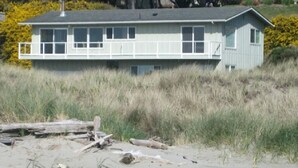 A two-story house with a flat roof, large windows, and a balcony. - Ocean Front ON the Beach - Spectacular Views! 14 Minutes to Bandon Dunes Golf! (Bandon)