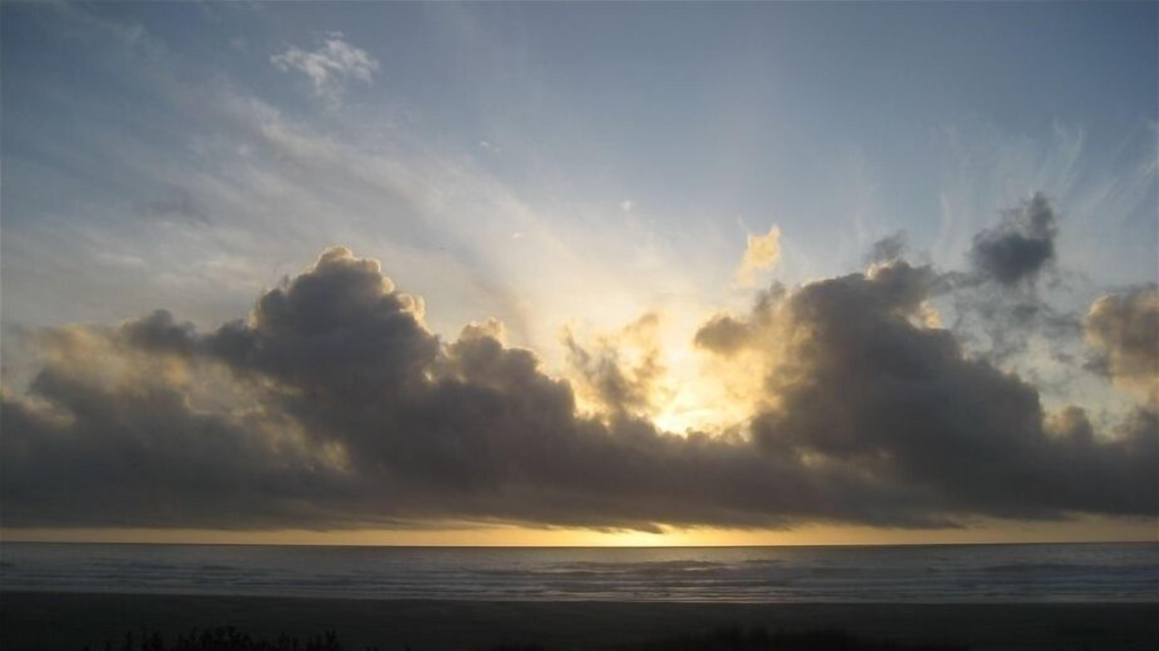 Een strand met een zonsondergang en wolken.