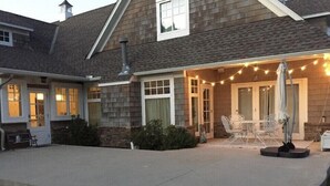 Een huis met een overdekte patio, buiten zitplaatsen en lichtjes.