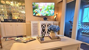 Ein Wohnzimmer mit Fernseher, einer Dekovase und einem Bücherregal.