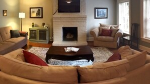 A living room with a fireplace, two sofas, a coffee table, and a television mounted on the wall. - The Garden Apartment with a Murphy Table (Savannah)