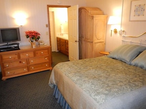 Relax in a traditional room with a dresser, TV, and comfortable bed.