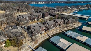 An aerial view of a residential area with multi-story buildings, a dock, and a body of water. - 22 Mile Marker! Indoor/Outdoor Pools, Hot Tub! New (Osage Beach)