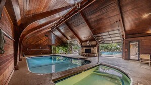 An indoor swimming pool with a wooden interior, a stone fireplace, and a view of the outdoors. - 22 Mile Marker! Indoor/Outdoor Pools, Hot Tub! New (Osage Beach)