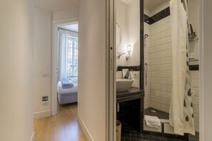 A modern bathroom with a shower, a sink, and a mirror. There is a towel rack and a basket on the floor. - Live at Domus Claudiae, be part of an art work (AirCond-WiFi) (Roma)