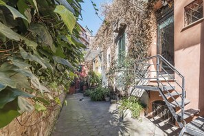 A narrow alleyway with a cobblestone path, a dog lying on the ground, and a staircase leading to a building. - Live at Domus Claudiae, be part of an art work (AirCond-WiFi) (Roma)