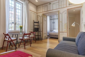 Una habitación con comedor, sofá, cama y escalera.