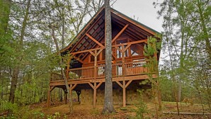 A wooden cabin with a balcony, surrounded by trees and a stone foundation. - *Beautiful Cabin With Gorgeous Views and Privacy*-Sunset Ridge (Sevierville)