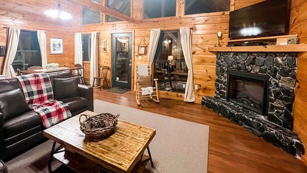 A cozy log cabin interior with a fireplace, a television, and a dining area. - *Beautiful Cabin With Gorgeous Views and Privacy*-Sunset Ridge (Sevierville)