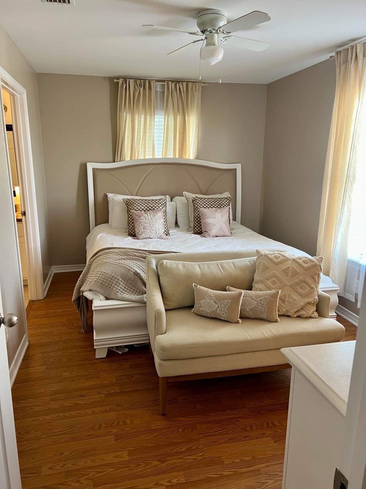 Ein Schlafzimmer mit Bett, Nachttisch, Sofa und Deckenventilator.