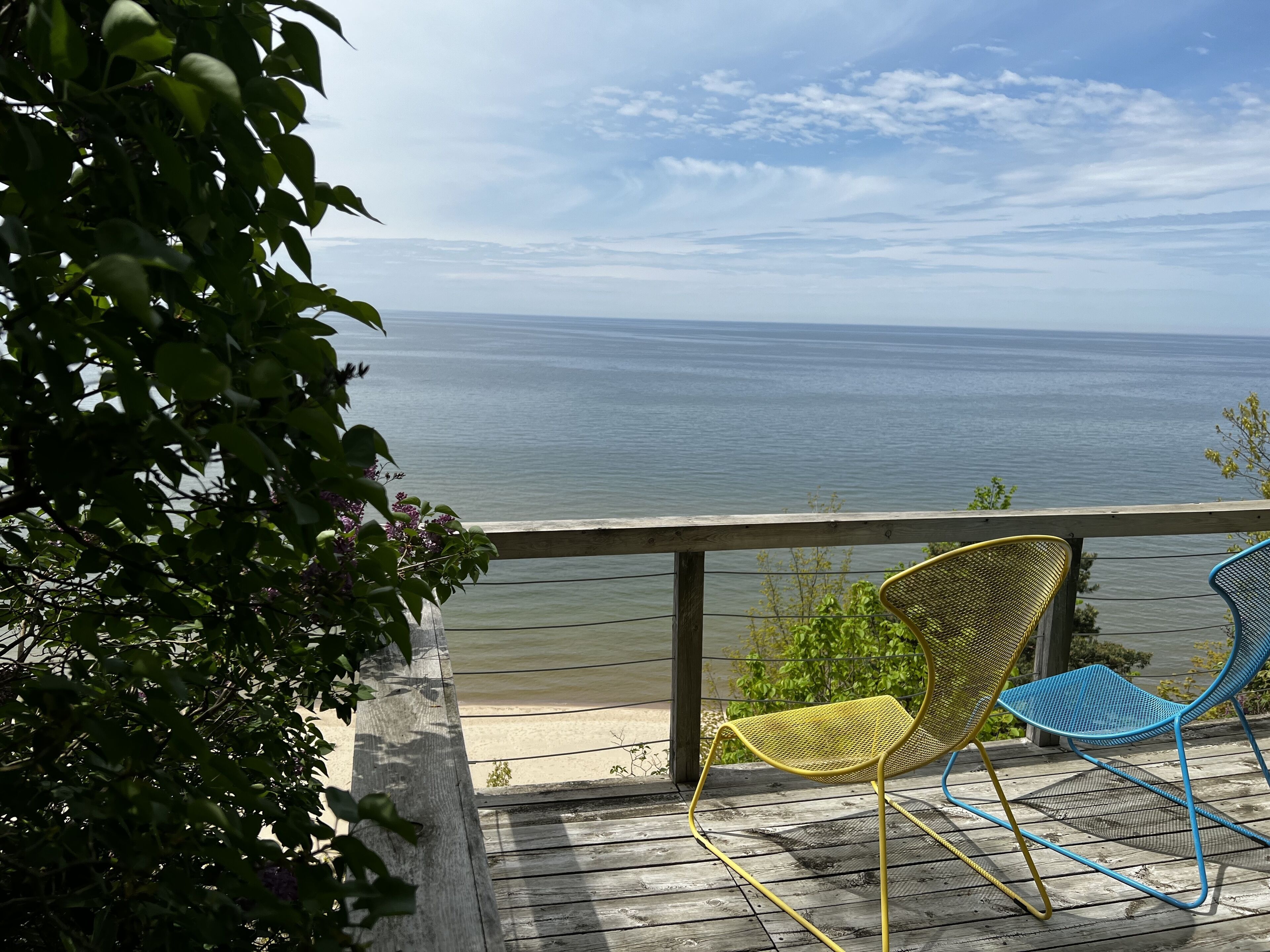 A wooden deck with two chairs overlooking a body of water.