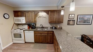 Una cocina con armarios de madera, microondas, estufa, lavamanos y encimera de granito.