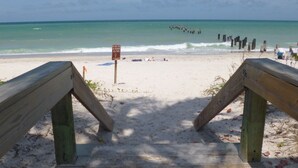 A wooden boardwalk leading to a sandy beach with a sign warning against picking or destroying sea glass. - In the heart of Old Naples (Naples)
