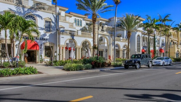 A street view of a hotel with a red awning, palm trees, and parked cars. - In the heart of Old Naples (Naples)