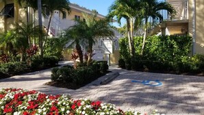 A courtyard with palm trees, a paved walkway, and a building with a balcony. - In the heart of Old Naples (Naples)