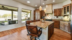 A spacious kitchen with a large island, wooden cabinets, and pendant lighting.