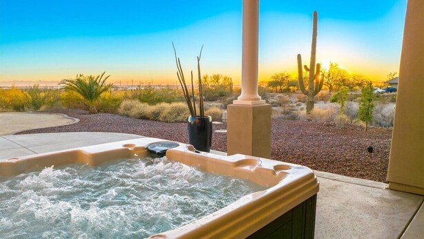 A hot tub with a view of a desert landscape, including cacti and a clear sky.