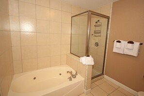 Een bad/douchecombinatie, een bubbelbad, handdoeken